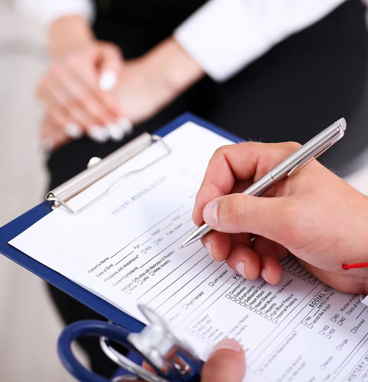 A person writes on a clipboard with a pen, focused on their task in a well-lit environment.